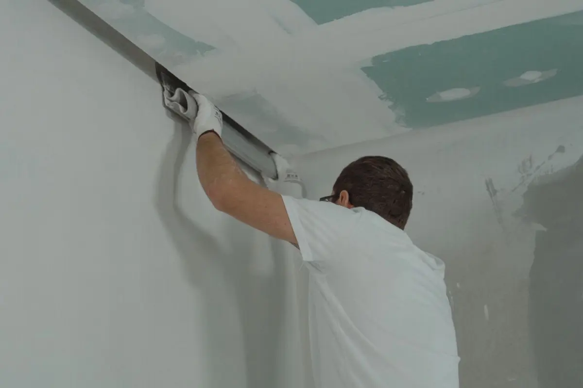 Plaquiste réalisant les joints d'un plafond en plaques de plâtre lors d'un doublage acoustique